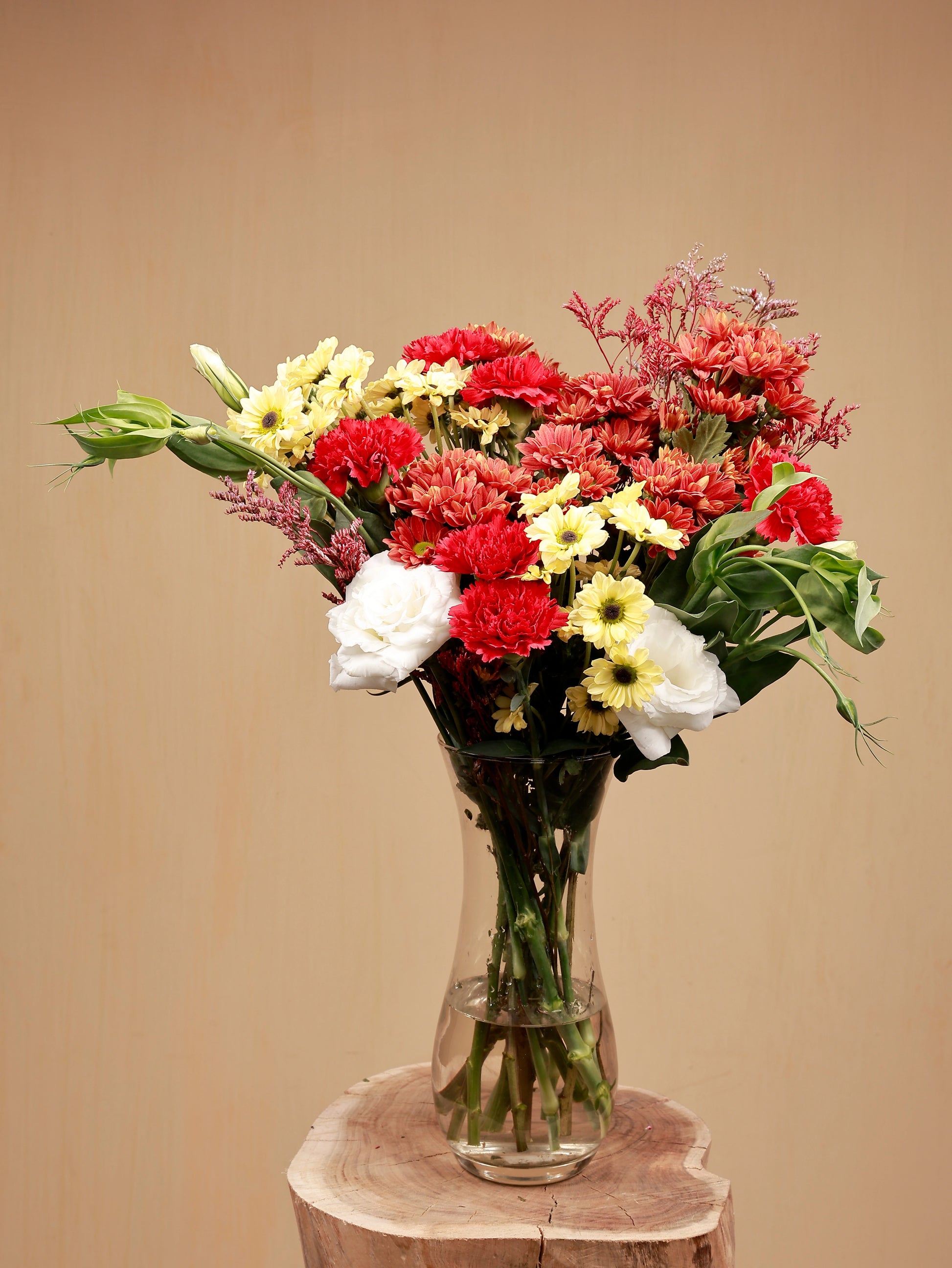 white eustoma with red carnations and other flowers in a glass vase